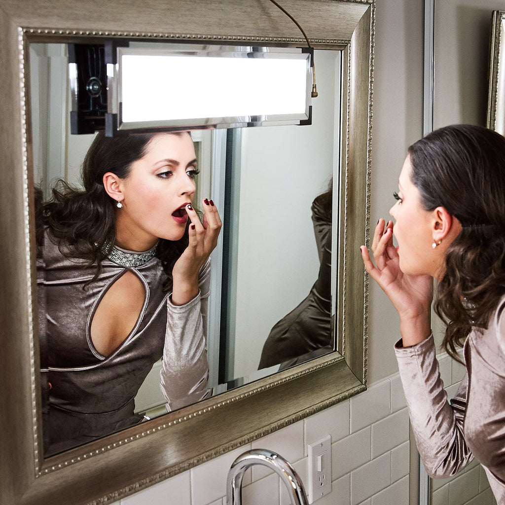 A model checks her lipstick in the mirror with an Eyelight hanging and illuminating her