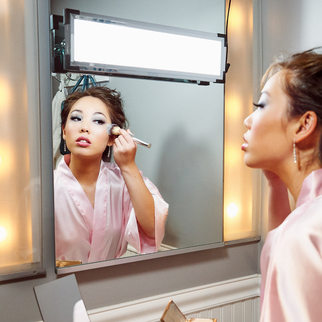 A woman adjusts her makeup in the light of her Eyelight Magic Kit, overwhelming the yellow hotel lights with daylight-balanced light