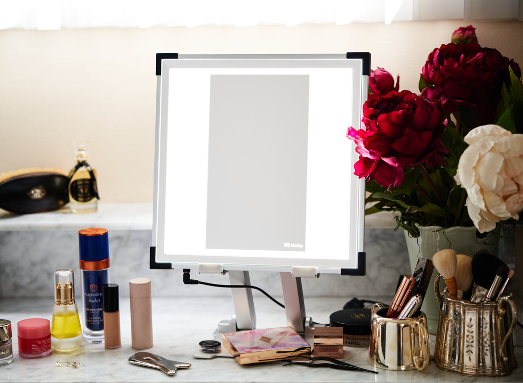A TML Meira tabletop sits on a counter with makeup products and flowers around
