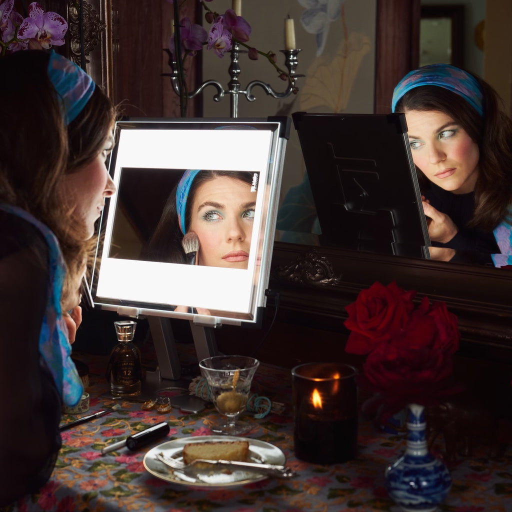 A woman looks at her reflection in the light of her lighted makeup mirror vanity, TML Meira