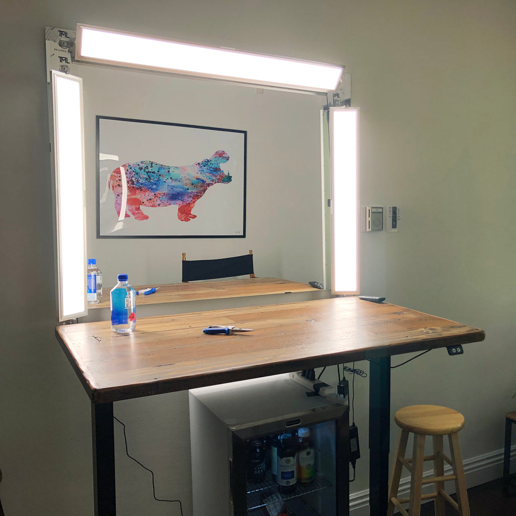 Three custom TML LED light panels set around a mirror in a custom studio with a table in front