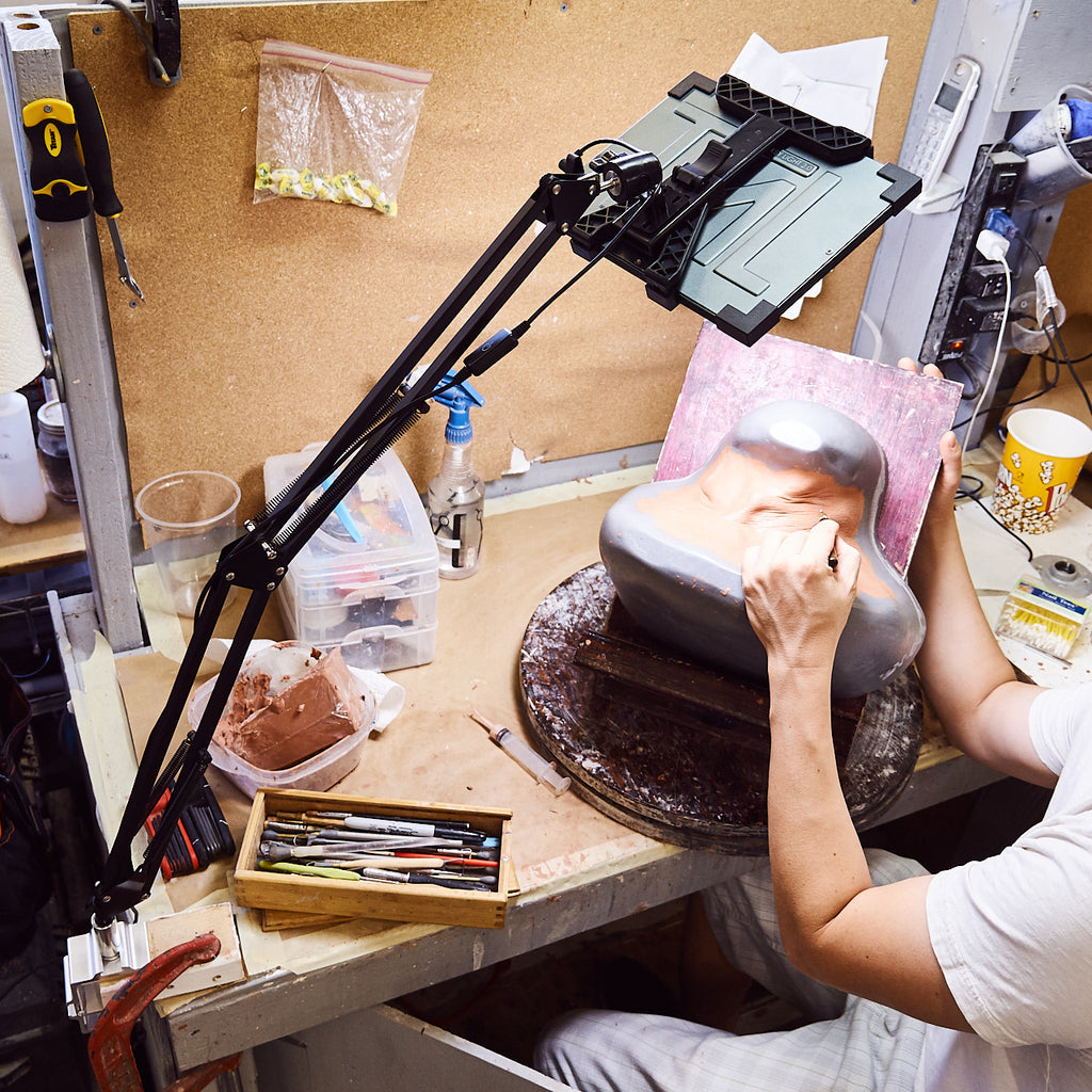A person works on a prosthetic mold with a Key Light on an Articulating Arm above