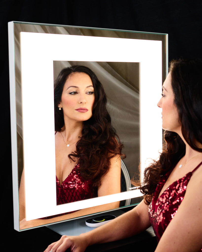 A woman in a red, sparkly dress regards her reflection in the TML Meira Home LUXe