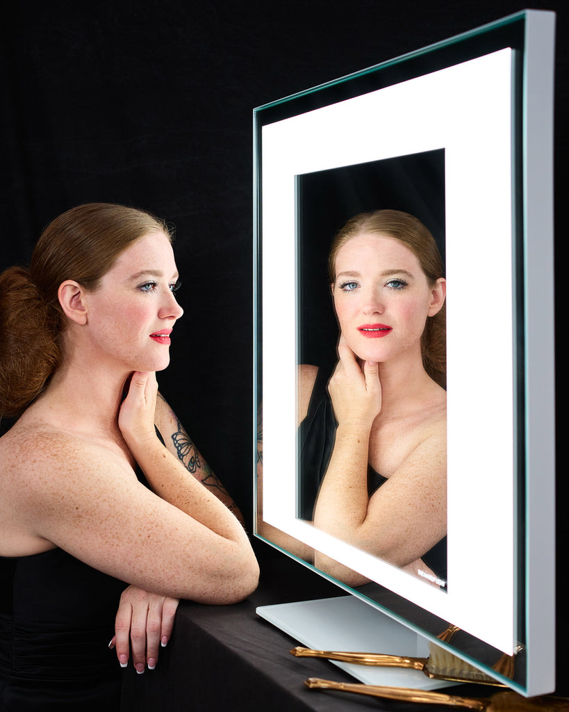 A woman sits in front of a TML Meira Home LUXe, smiling at the camera in the reflection.